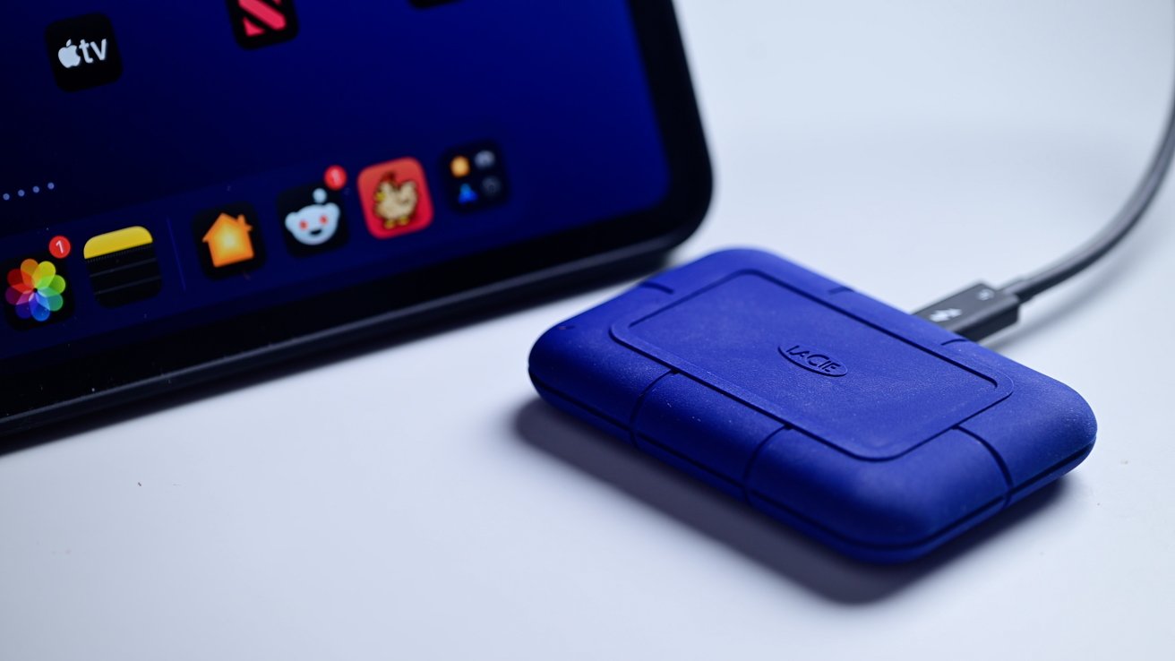 Tablet with colorful app icons on screen next to a connected blue external hard drive marked 'LaCie'.